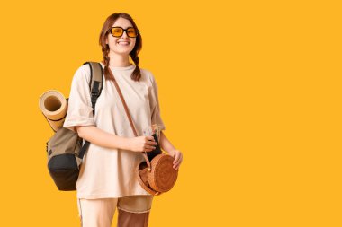 Genç bir kadın sarı arka planda pasaportunu ve biletini çantasına koyuyor. Seyahat kavramı