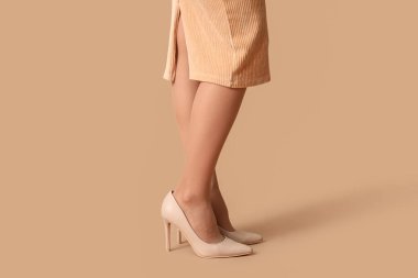 Tayt ve etekli bej arka planda genç bir kadın.