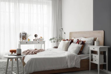 Yatak odasındaki pencerenin yanındaki masada küçük bir kozmetik buzdolabı.