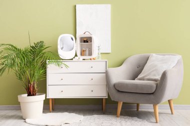 Küçük buzdolabı, kozmetik ürünleri ve oturma odasındaki yeşil duvarın yakınındaki çekmecelerin üzerindeki boya.