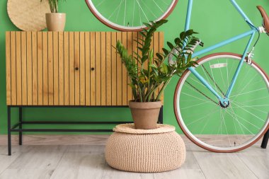 Yeşil duvarın yanında çekmeceleri ve bisikleti olan modern koridorun içi.