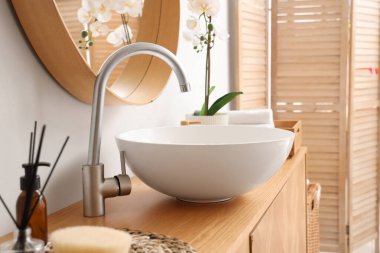 Lavabosu, aynası ve banyo aksesuarları olan ahşap dolap şık banyoda, yakın plan.