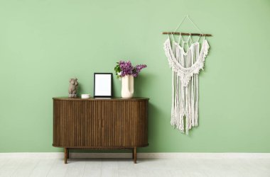 Şık oturma odasındaki çekmecelerin üzerinde leylak dalları olan heykel ve vazo.