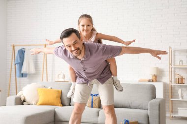 Baba ve küçük kızı oturma odasında birlikte oynuyorlar. Babalar günü kutlaması.