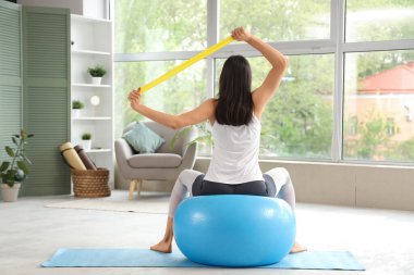 Lastik bant eğitimi almış, spor yapan genç bir kadın.