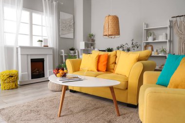 Sarı kanepesi, şöminesi ve bitkileri olan oturma odasının içinde.