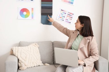 Ofisteki kumaş örneklerini gösteren dizüstü bilgisayarı olan güzel bir iç mimar.