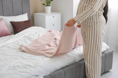 Evde pijamalı hamile bir kadın pembe ekose giyiyor.