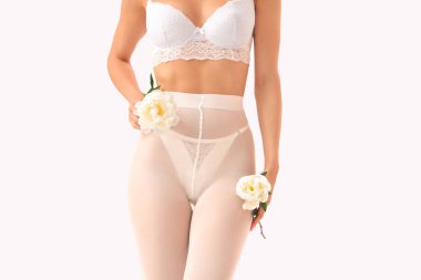 Beyaz arka planda şakayık çiçekleri olan şık iç çamaşırlı güzel bir genç kadın.