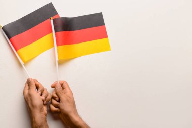 Beyaz arka planda Almanya bayrakları olan erkek eller