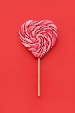 Kırmızı arka planda tatlı kalp şeklinde lolipop. Sevgililer Günü kutlaması