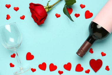 Mavi arka planda Sevgililer Günü için şarap, cam, kalp ve gül çiçekli bir çerçeve.