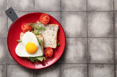 Lezzetli kızarmış yumurta, tost, domates ve arkaplanda roka.
