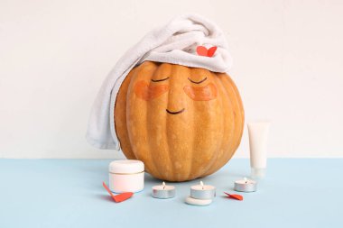 Çizilmiş yüzlü balkabağı, spa malzemeleri, kağıt kalpler ve mavi masanın altında göz altı yamaları.