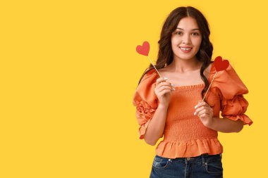 Sarı arka planda kırmızı kağıt kalpli güzel bir Asyalı kadın. Sevgililer Günü kutlaması