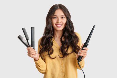 Saç maşası ve hafif arka planda tarakları olan Asyalı genç bir kadın.