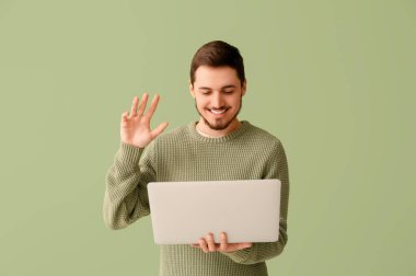 Laptop 'u olan yakışıklı genç adam yeşil arka planda sohbet ediyor. Çevrimiçi randevu kavramı