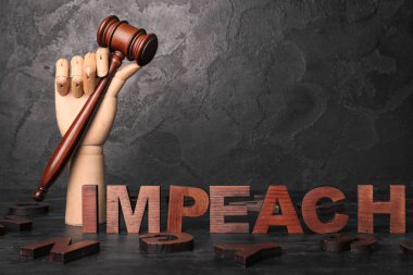 Hakim tokmağı olan tahta el ve siyah grunge arka planda IMPEACH sözcüğü