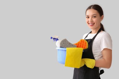 Hafif arka planda temizlik malzemesi olan genç bir kadın.