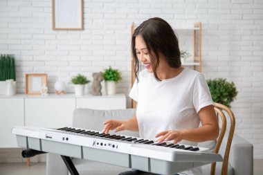 Evde sentezleyici çalan genç bir kadın.