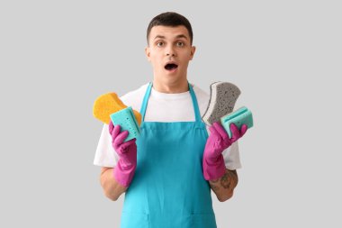 Açık arka planda bir sürü süngeri olan şaşırmış genç bir adam.