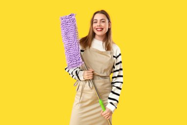 Sarı arka planda paspası olan güzel bir kadın.