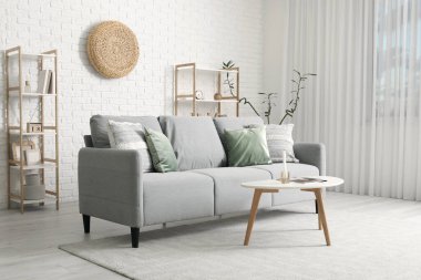 Gri kanepe, masa ve raf üniteleriyle modern oturma odasının içinde.