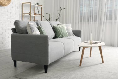 Gri kanepesi, masası ve raf ünitesi olan modern oturma odası.