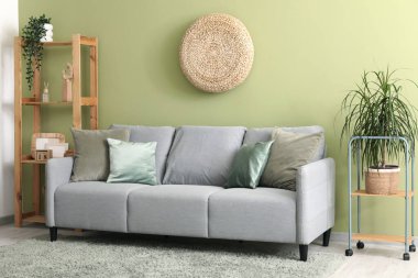 Gri kanepeli, puf ve raf üniteli şık bir oturma odası.