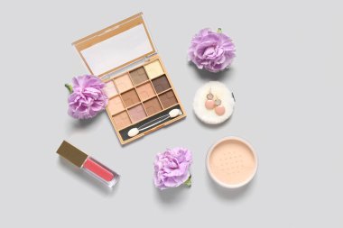 Küpeli dekoratif kozmetik ürünler ve beyaz arka planda çiçekler