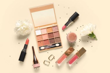 Bej arka planda küpeli, çiçekli ve konfetili makyaj ürünleri