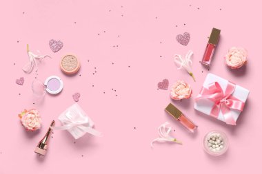 Hediye kutuları, çiçekler ve pembe arka planda konfeti olan makyaj ürünleri.