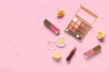 Güllü makyaj ürünleri ve pembe arka planda konfeti.
