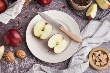 Koyu arkaplanda taze kırmızı elma ve ceviz tabağı.