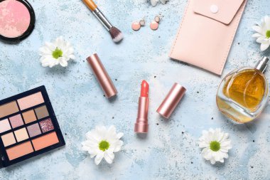 Mavi grunge arka planda fırçalar, papatyalar ve parfüm şişeleri için makyaj malzemeleri