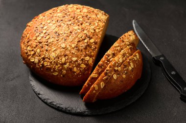 Siyah zemin üzerinde dilimlenmiş ekmek ve bıçak olan tahta.