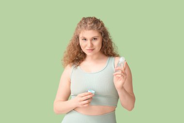Yeşil arka planda deodorantı olan güzel genç bir kadın.