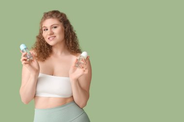 Yeşil arka planda deodorantları olan güzel genç bir kadın.