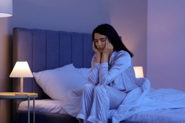 Beautiful young woman suffering from insomnia in bedroom at night