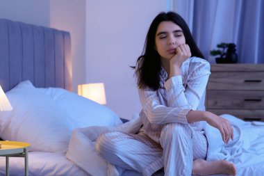 Beautiful young woman suffering from insomnia in bedroom at night