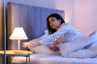 Beautiful young woman suffering from insomnia in bedroom at night