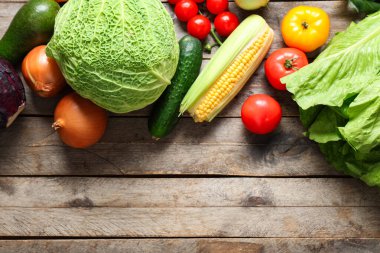 Gri ahşap arka planda farklı taze sebzeler.