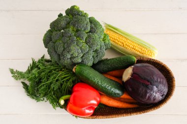 Hasır kase beyaz ahşap arka planda farklı taze sebzelerle