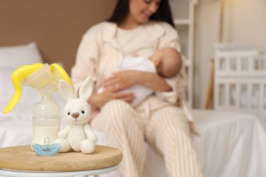 Bebek emziği ve oyuncağı olan meme pompası yatak odasında, yakın plan.