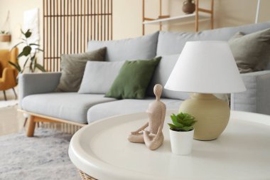 Oturma odasındaki masada üzerinde çiçek ve biblo olan lamba, yakın plan.