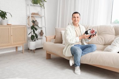 Hediye gözlüklü genç adam evdeki kanepede oturuyor.