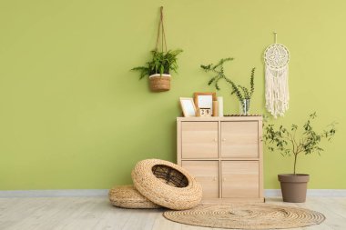 Okaliptüs dallı vazo. Odadaki yeşil duvarın yanındaki çekmecelerin üzerinde.