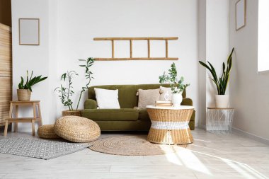 Çiçek, rahat bir kanepe ve okaliptüs dalları güzel bir odadaki sehpanın üzerinde.