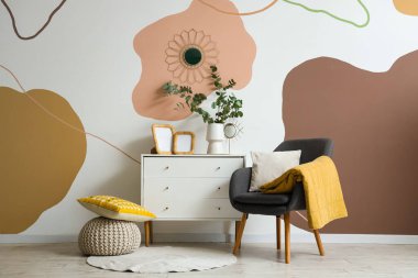 Koltuk, fotoğraf çerçeveleri ve okaliptüs dallarıyla dolu vazolar güzel odadaki çekmecelerin üzerinde.