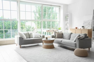 Oturma odasının içinde kanepeler, rattan masa ve yumuşak halı var.